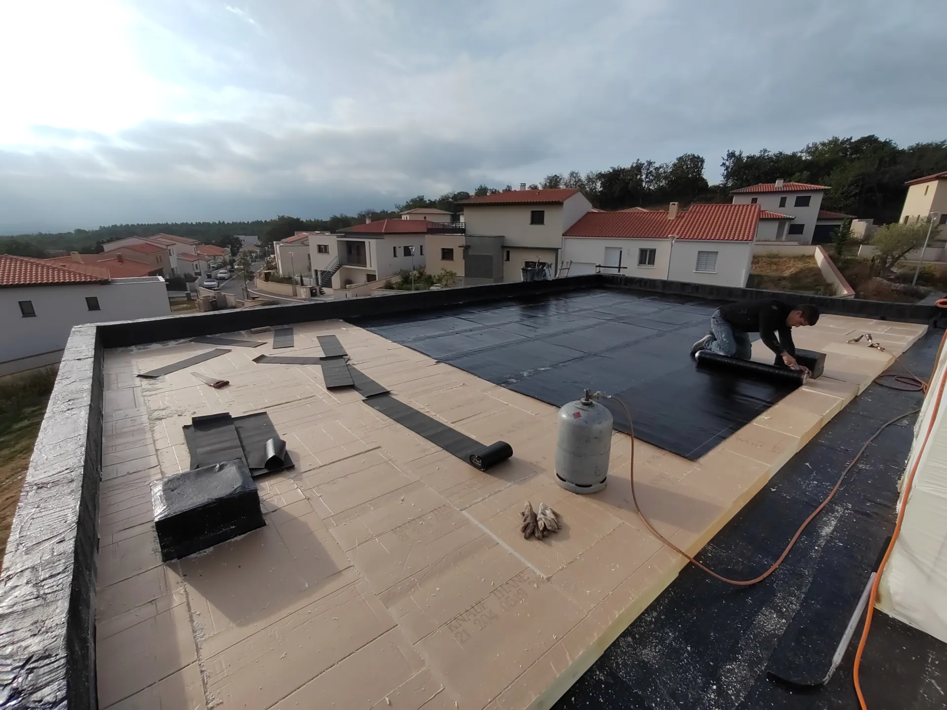 Artisan étancheur au travail — soudure de membrane bitumineuse au chalumeau sur toiture-terrasse